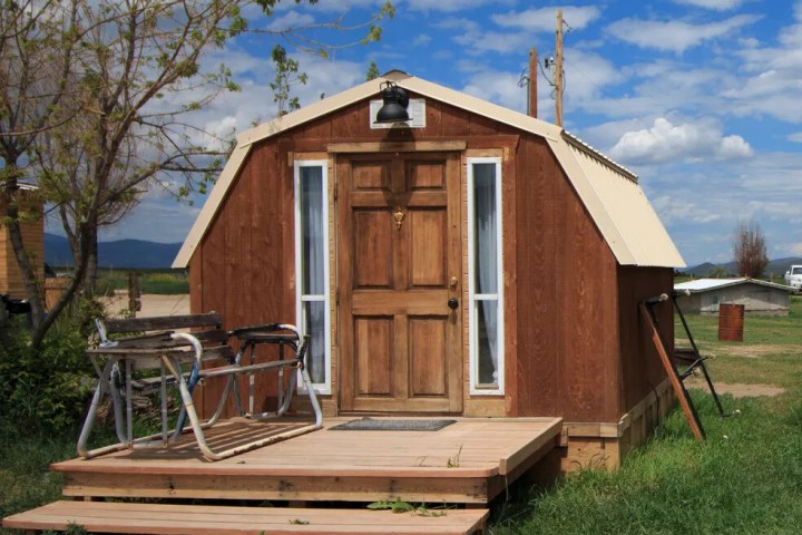 Small wooden cabin with a porch under a clear sky.