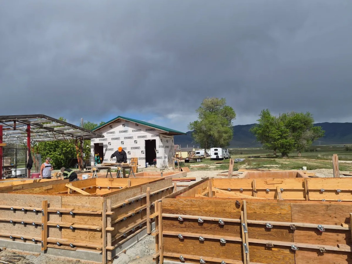 Construction site with wooden forms and building under cloudy sky.